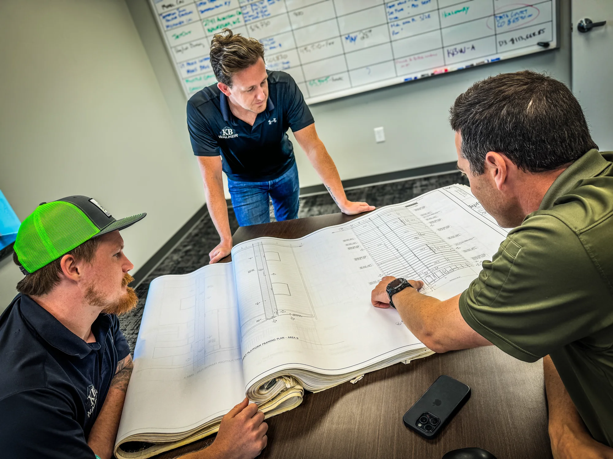 Construction team reviewing a large printed plan set around a table